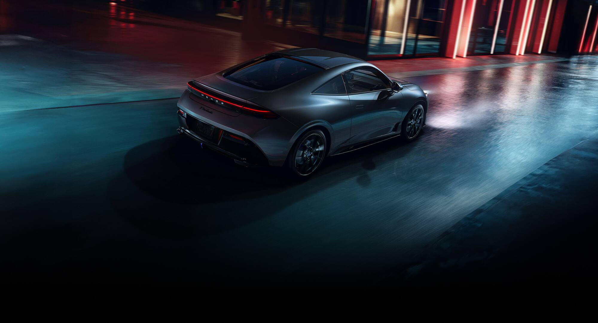 2027 Honda Prelude Hybrid in Meteorite Gray Metallic back driving through a city street at night (exhilarating hybrid coupe).